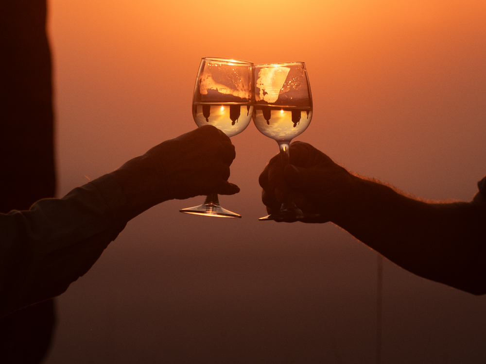 Priska und Hansruedi stossen mit einem Glas Wein an. Im Sonnenlicht reflektieren die Massai